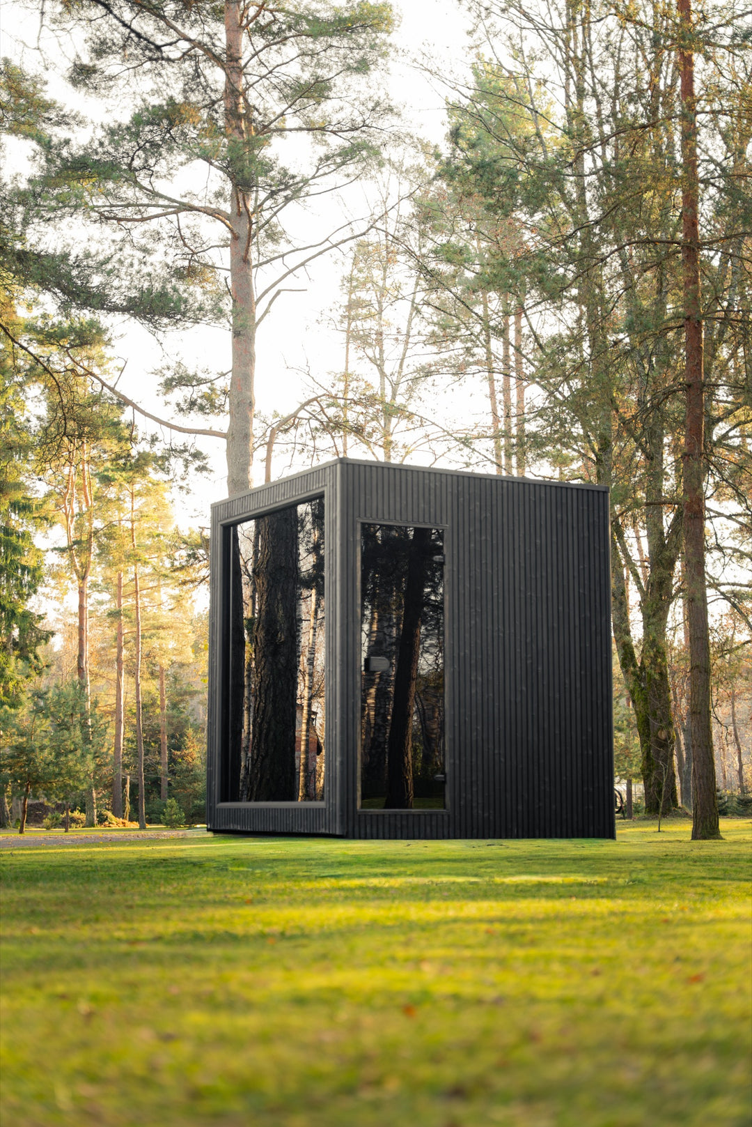 Sauna ogrodowa VALO S z czarną elewacją i szklanym frontem wśród sosen w parku