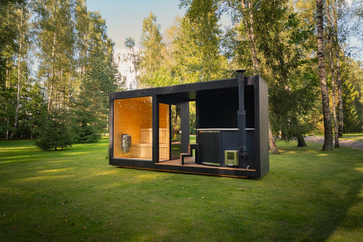 Gartensauna mit Badezuber KOTI L auf einer Wiese zwischen Birken – Sauna, überdachte Terrasse und Zuber in einem Baukörper